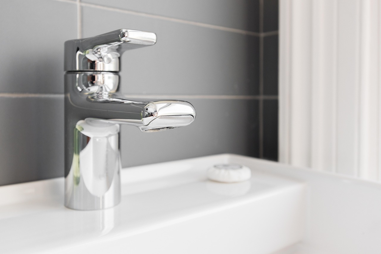 Chrome basin mixer tap on a white sink against grey tiles