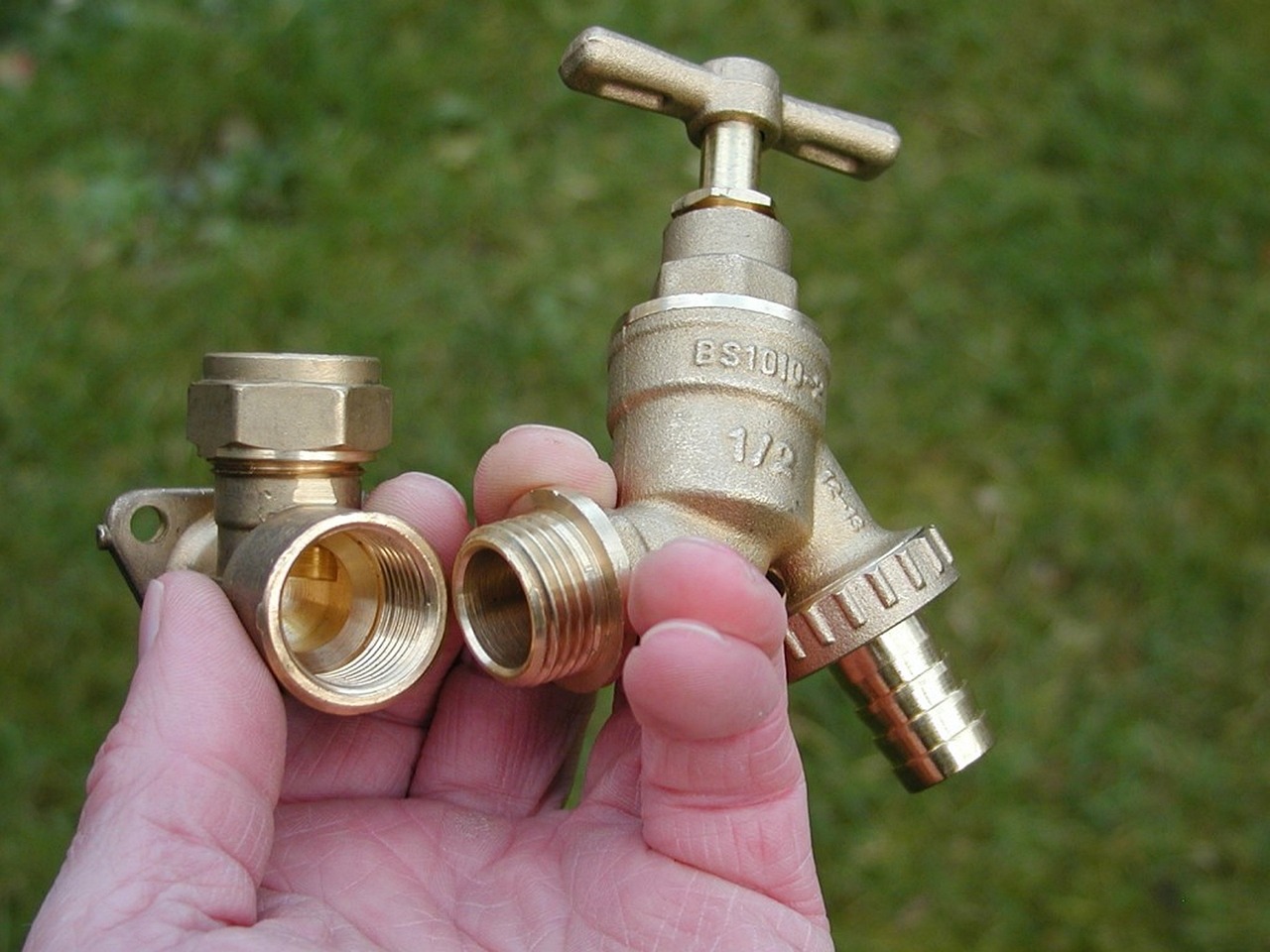 Hand holding brass tap and pipe fittings
